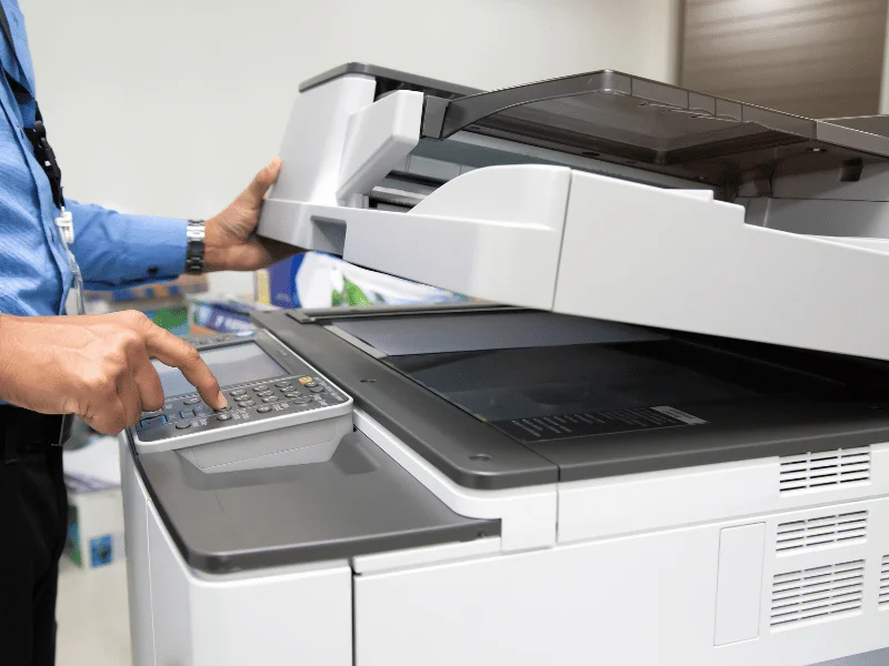 Person pressing start button on a photocopier machine.